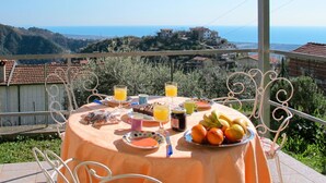 A table set outdoors with a view of a hillside and a distant building. - Cosy apartment for 6 people with WIFI, TV, patio and pets allowed (Montignoso)
