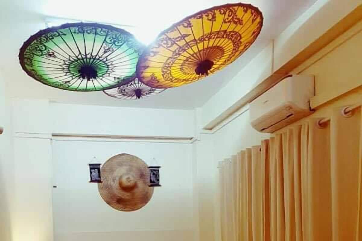 A hotel room with a bed, a nightstand, a lamp, a wall-mounted light fixture, and a window with curtains.