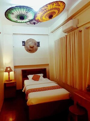 A hotel room with a bed, a nightstand, a lamp, a wall-mounted light fixture, and a window with curtains. - Lei Lei's place (Yangon)
