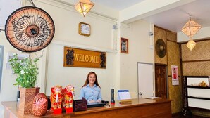 En receptionsdisk med en skylt som visar ”VÄLKOMMEN!”, en klocka och dekorativa föremål, inklusive statyetter av en uggla och en elefant.
