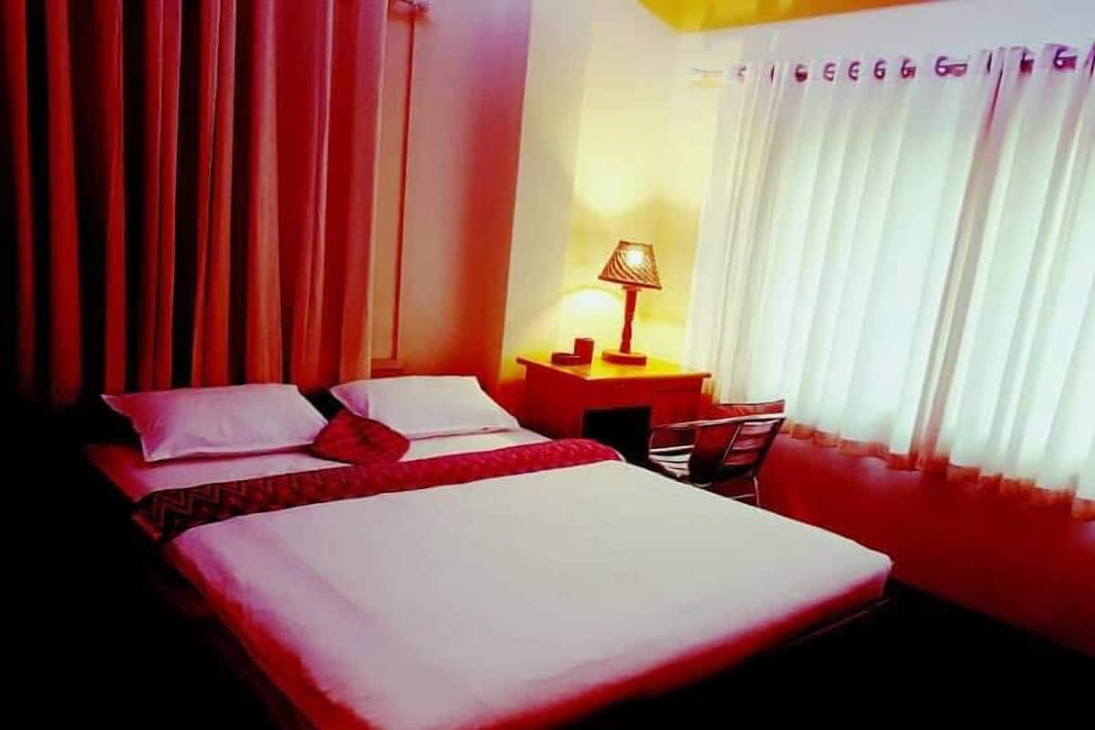 A hotel room with a bed, a nightstand, a lamp, and a chair.
