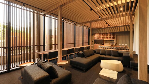 Un'area relax moderna con un divano componibile, un tavolino rotondo e un angolo bar con scaffali pieni di bottiglie.