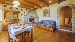 Ein gemütliches Wohnzimmer mit Kamin aus Stein, Holzmöbeln und einem Essbereich, der für eine Mahlzeit gedeckt ist.