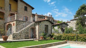 A stone building with a swimming pool, surrounded by a well-maintained garden and a clear sky. - Lovely apartment for 6 guests with private pool, WIFI, A/C, TV, terrace and pets allowed (Lugliano)