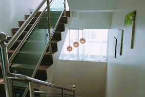 A modern staircase with glass railings and a view of the sky through a window. - Ok Family Villa (Ipoh)