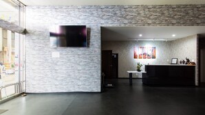 Ett modernt receptionsområde med en vägg av natursten, en platt-TV och en receptionsdisk.