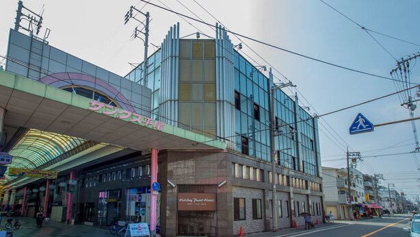 En modern byggnad med en glasfasad, en övergångsskylt för fotgängare och en skylt för hotellet Holiday Pearl.