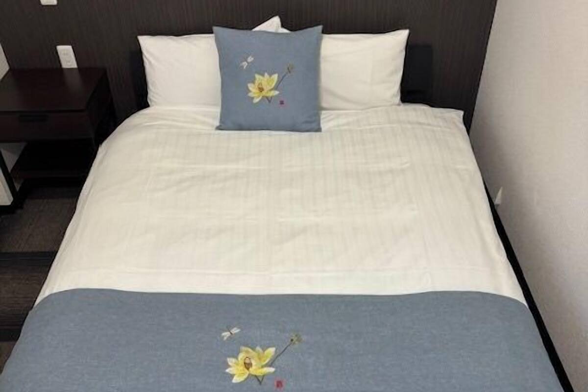 A neatly made bed with a blue pillow and a floral bedspread.