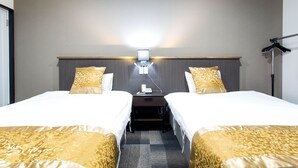Ett hotellrum med två separata sängar, ett nattduksbord, en lampa och en väggmonterad lamparmatur.