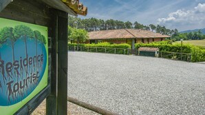 Un panneau indiquant un site touristique résidentiel, avec un chemin de gravier menant à un bâtiment doté d’un toit en tuiles.
