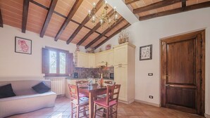 A spacious kitchen with wooden beams, a dining area with a table and chairs, and a cozy seating area with a sofa. - Wonderful private villa for 4 people with A/C, WIFI, TV, patio and pets allowed (Lucca)