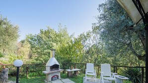 An outdoor patio with a stone pathway, a stone barbecue grill, white outdoor furniture, and a pergola. - Wonderful private villa for 4 people with A/C, WIFI, TV, patio and pets allowed (Lucca)