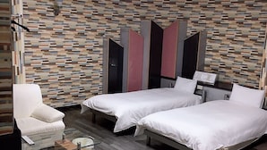 Habitació d'hotel amb dos llits, un sofà, una taula petita i una decoració mural.
