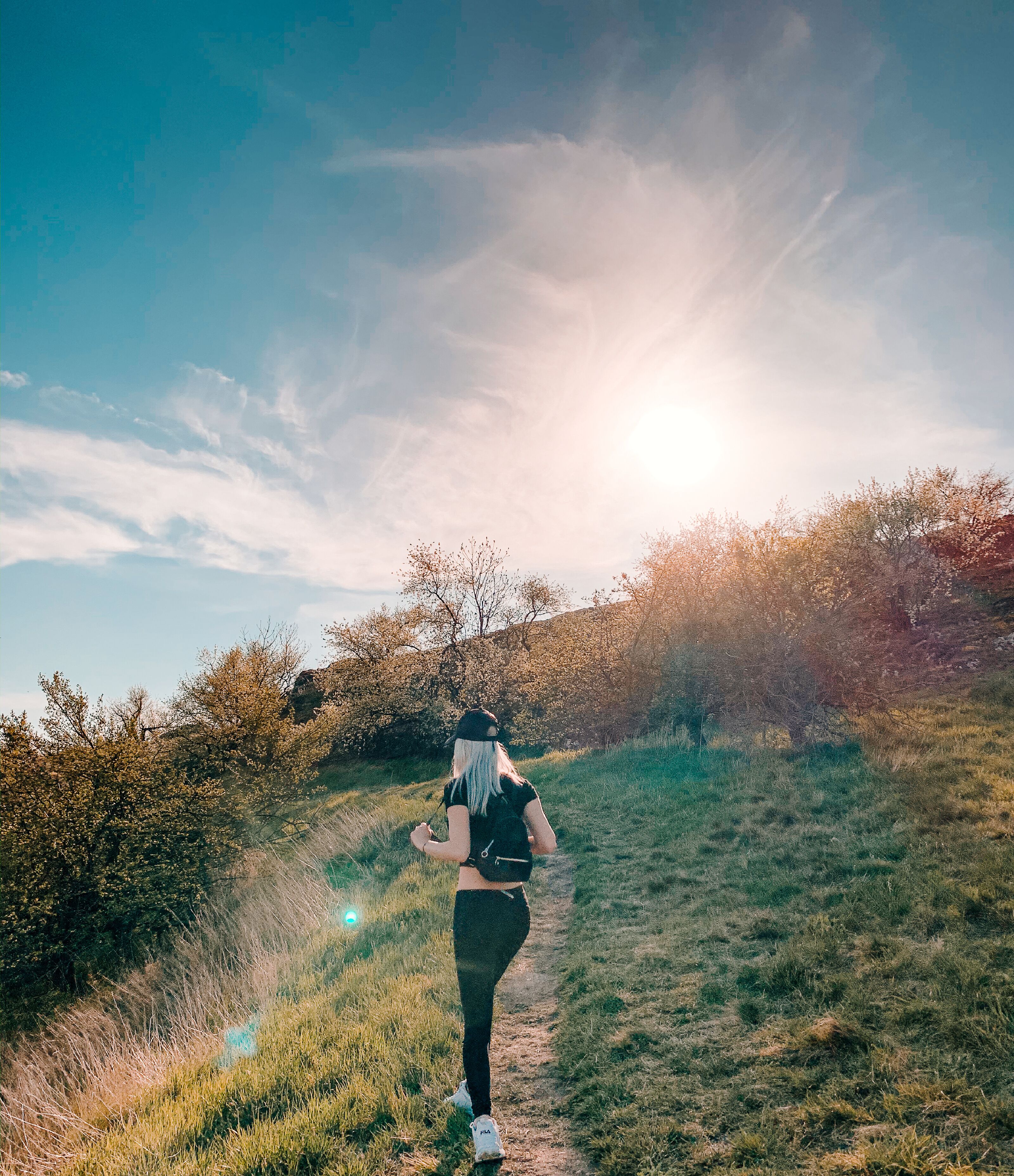 A person walking on a grassy path with trees and bushes on either side.