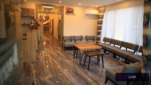 A modern living room with a marble floor, a sofa set, a coffee table, and a kitchen area with wooden cabinets. - Butterfly Butik Hotel (Kirklareli)