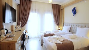 A hotel room with two beds, a desk with a flat-screen TV, a coffee maker, and a view of the outdoors through large windows with curtains. - Butterfly Butik Hotel (Kirklareli)