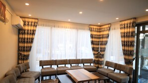A room with a sofa set, a wooden table, and curtains with a leaf pattern. - Butterfly Butik Hotel (Kirklareli)
