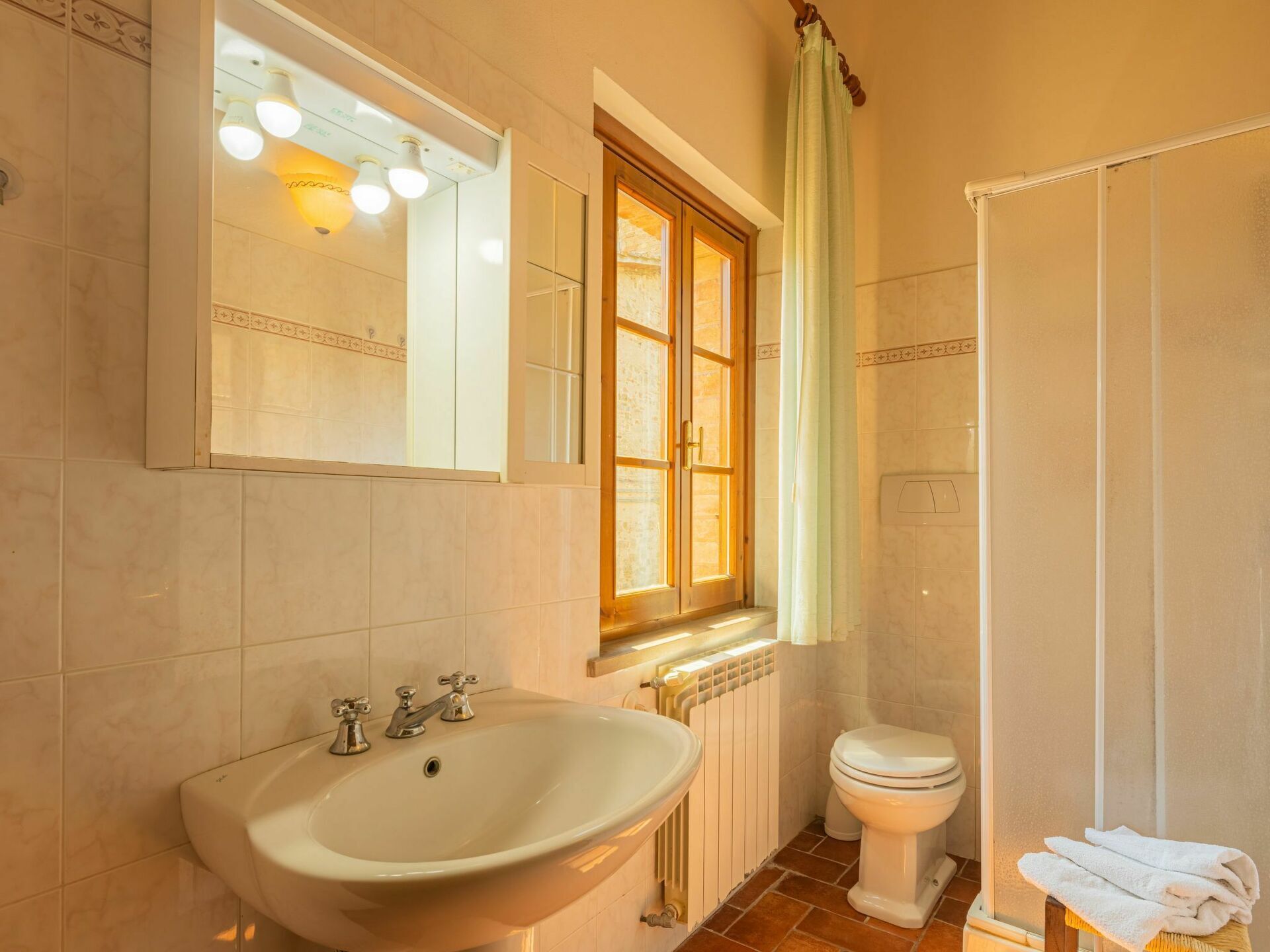A bathroom with a sink, toilet, and a window with curtains.