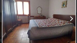 A bedroom with a bed, a dresser, a chair, a window with curtains, and a picture on the wall. - Apartment 117 M² in a beautiful condominium house  (Arzachena)