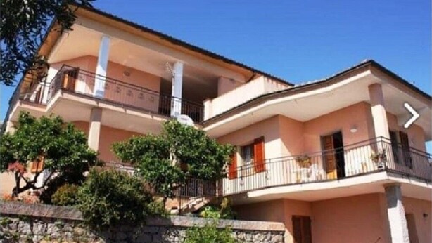 A two-story building with balconies, a stone wall, and trees. - Apartment 117 M² in a beautiful condominium house  (Arzachena)