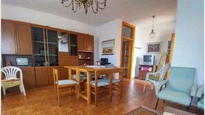 A living room with a dining table and chairs, a television, and a sofa. - Apartment 117 M² in a beautiful condominium house  (Arzachena)