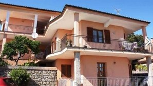 A two-story building with balconies, a stone wall, and a clear sky. - Apartment 117 M² in a beautiful condominium house  (Arzachena)