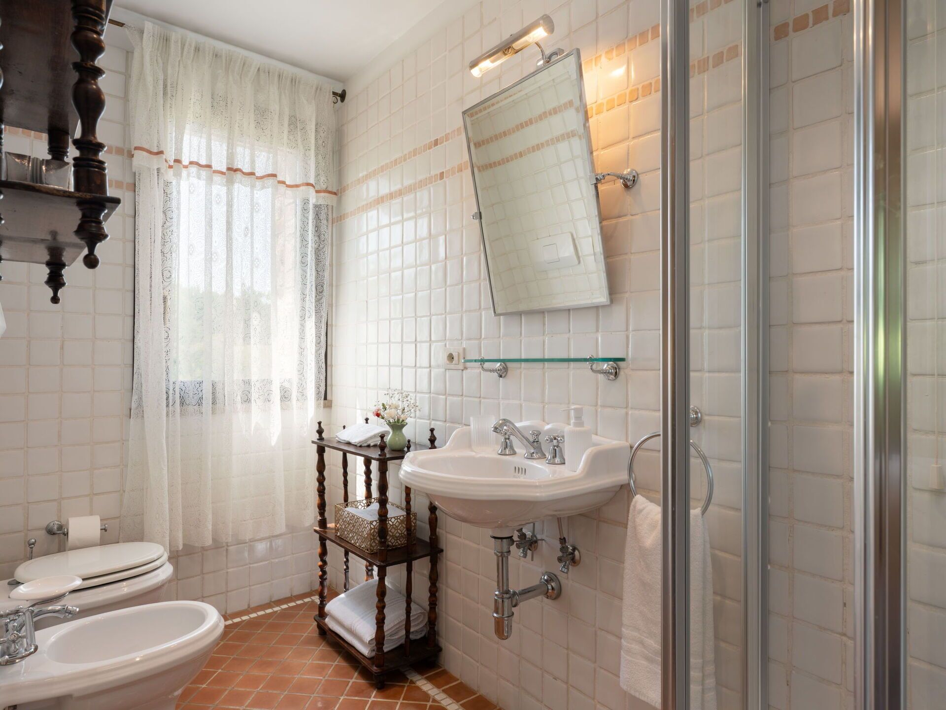 Een badkamer met toilet, bidet, wastafel en een douche met glazen wanden.