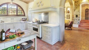 Cozinha espaçosa com armários brancos, um fogão grande e um espaço de refeições com um sofá vermelho.