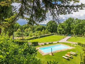 Ein Pool, umgeben von einem gepflegten Garten mit verschiedenen Pflanzen und Bäumen.
