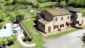Un bâtiment à deux étages doté d’une piscine, entouré d’une végétation luxuriante et de collines.