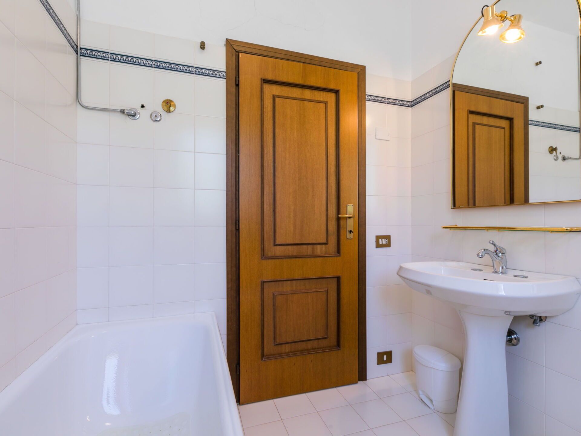A bathroom with a wooden door, a white sink, and a bathtub.