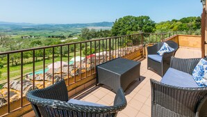 Un balcon doté de meubles en osier et offrant une vue sur un paysage verdoyant.