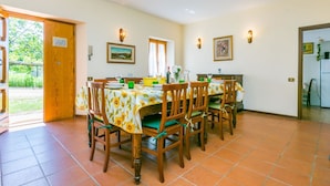 Un coin repas avec une table dressée pour quatre personnes, entourée de chaises en bois dotées de coussins verts.