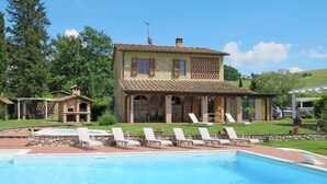 Una casa a due piani con piscina, area relax all'aperto e giardino.