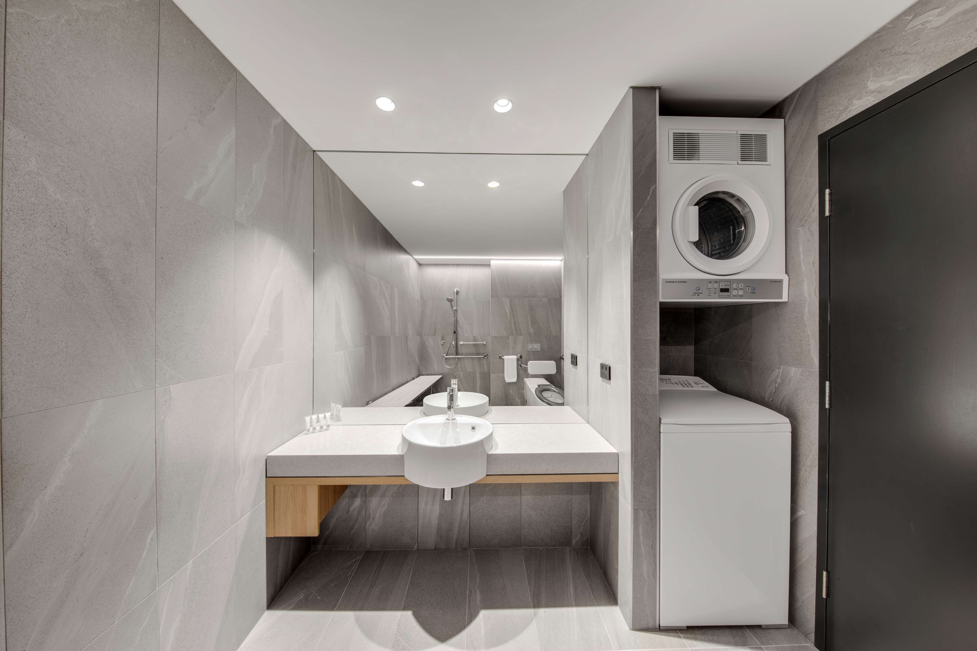 A modern bathroom with a built-in washing machine, a sink, and a mirror.