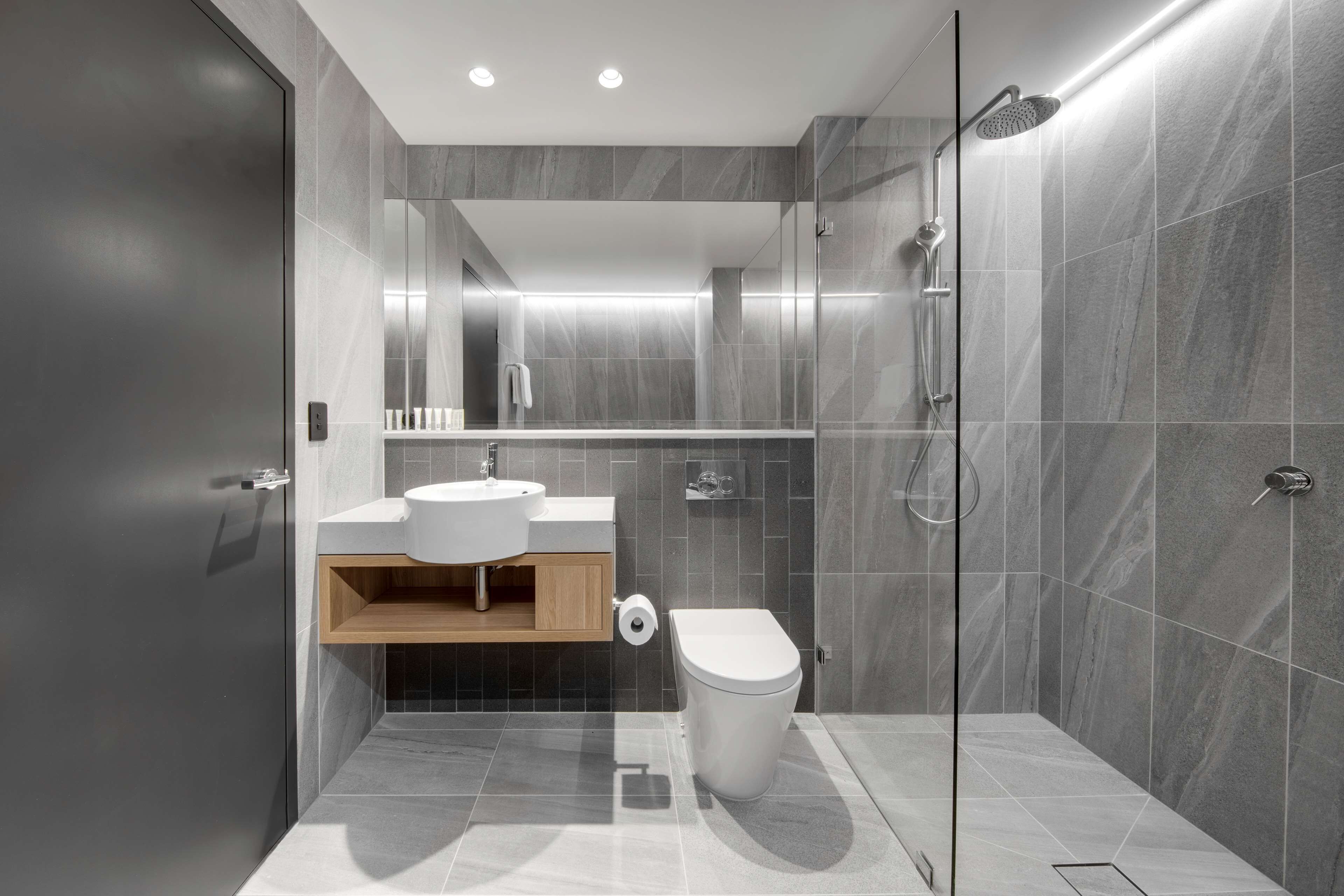 A modern bathroom with a shower, toilet, and sink.