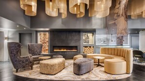 A modern lounge area with a fireplace, seating arrangements, and a large abstract artwork.