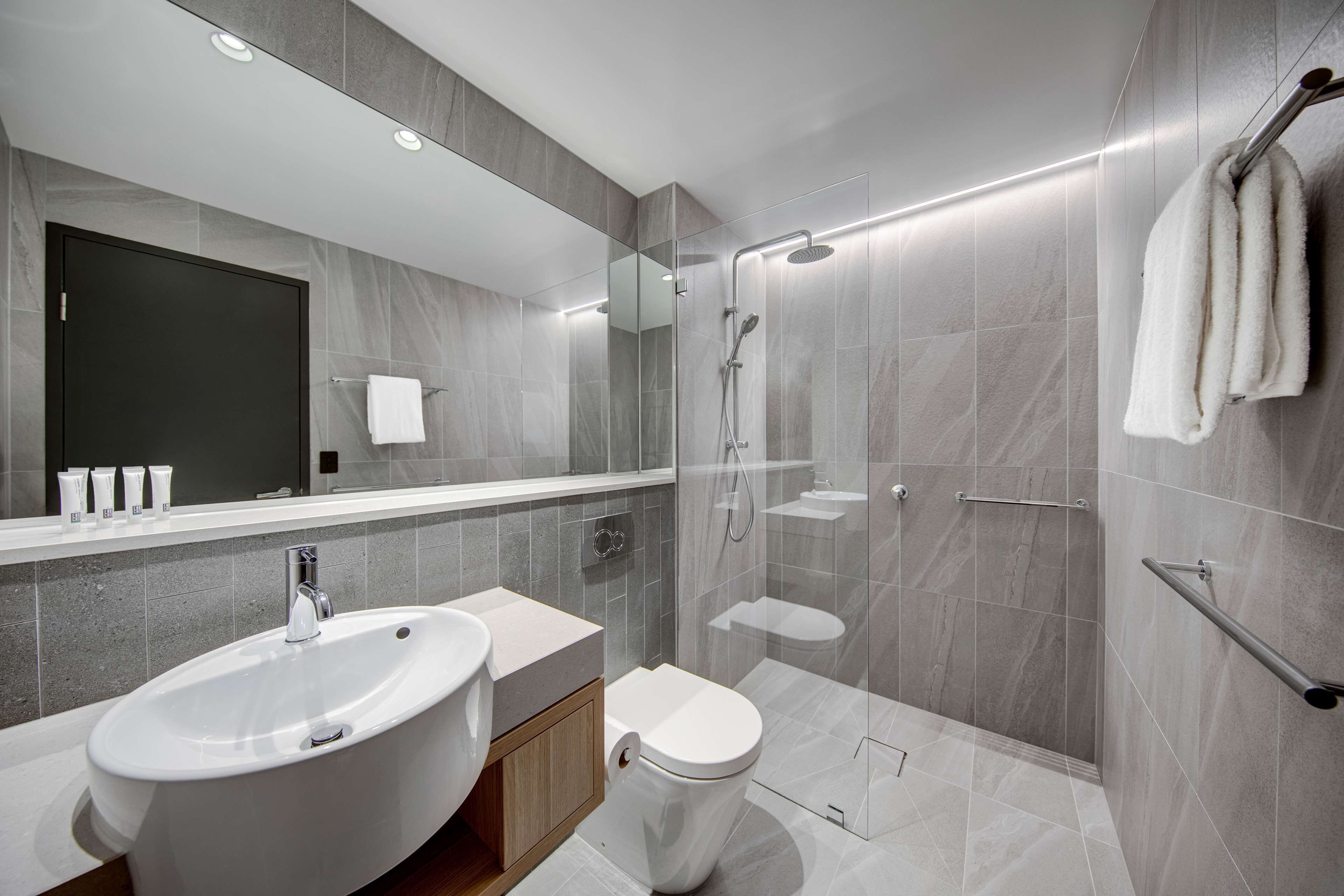 A modern bathroom with a large sink, toilet, and glass-enclosed shower.