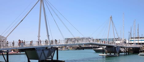 Un puente peatonal sobre un cuerpo de agua, con barcos amarrados cerca.