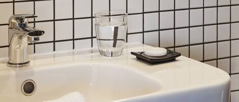 Een badkamer met een witte wastafel, een glas water en een handdoek.