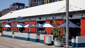 A restaurant with outdoor seating, red and white exterior, and string lights. - Travelodge Hotel Auckland Wynyard Quarter (Auckland)