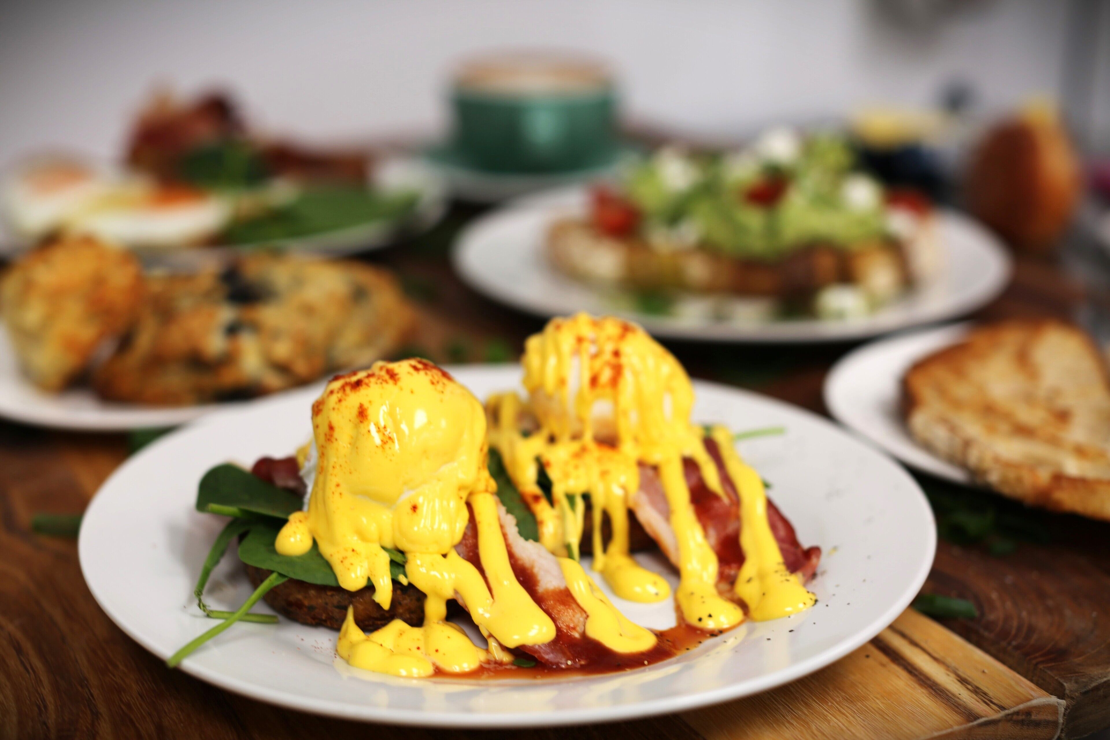 Un desayuno con un plato de huevos benedictinos y otras preparaciones.
