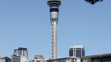 Una torre moderna con guglia, circondata da edifici urbani e un porto turistico.