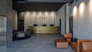 A modern reception area with a central counter, seating, and a decorative wall. - Travelodge Hotel Auckland Wynyard Quarter (Auckland)