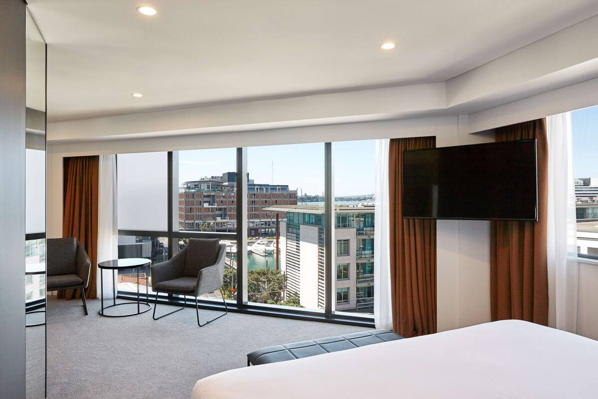 Hotellihuone, jossa on suuri ikkuna, sänky, työpöytä ja tuoli.