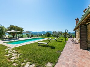 Ein Garten mit Swimmingpool, Liegestühlen und einer Pergola.