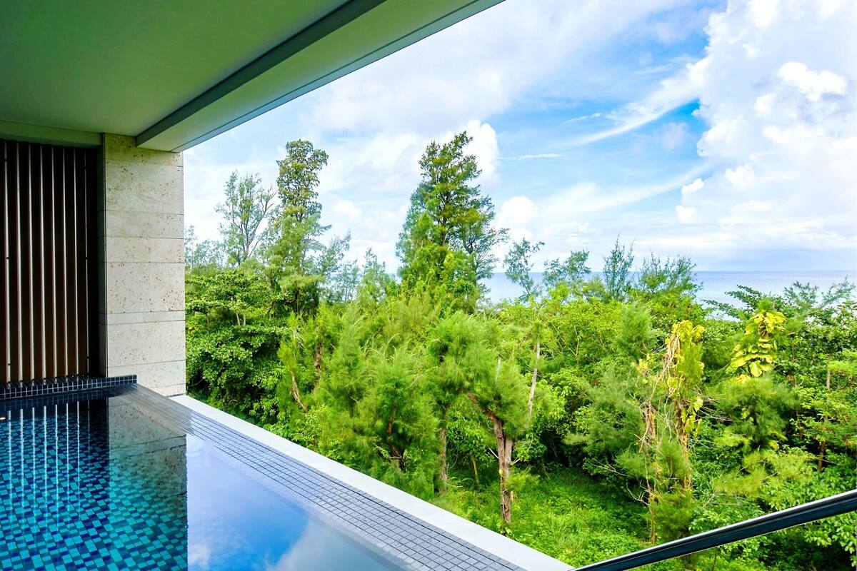 A modern infinity pool with a clear view of lush greenery and trees.
