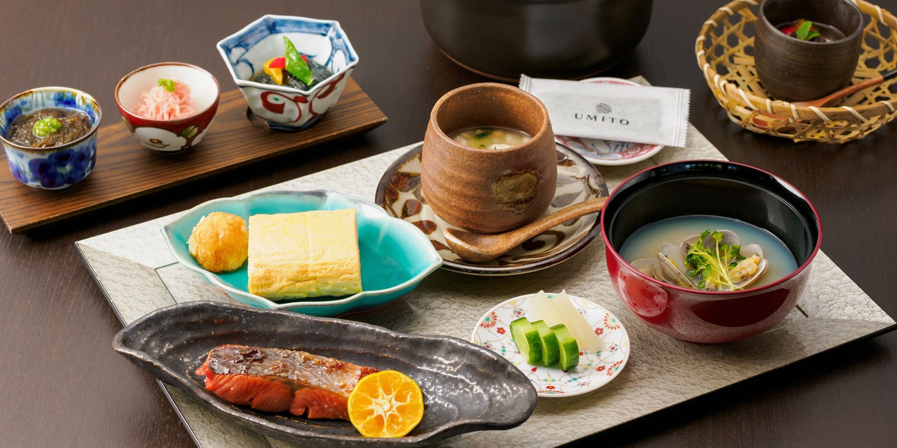 Una comida tradicional japonesa con diversos platos, incluyendo pescado, verduras y sopa.