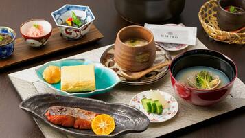 Una comida tradicional japonesa con diversos platos, incluyendo pescado, verduras y sopa.