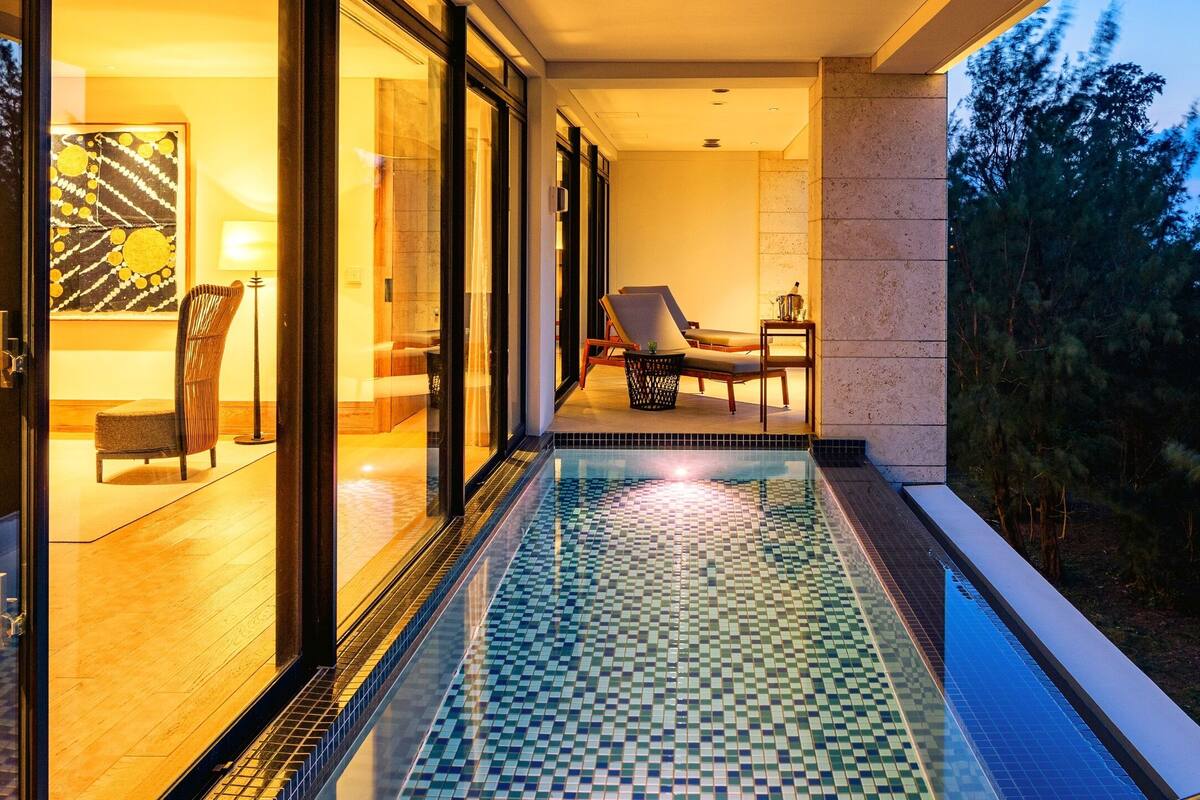 A modern hotel room with a glass door leading to a balcony with a pool.